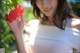 A woman holding a red flower in her hand.