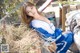 A woman in a blue and white outfit sitting on a pile of hay.