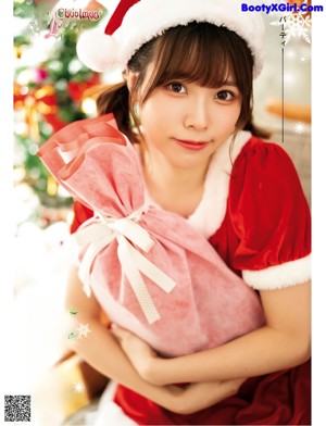A woman in a santa hat holding a pink bag.