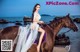 A woman in a wedding dress riding a horse on the beach.