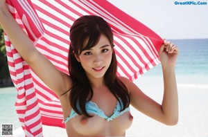 A woman in a blue bikini holding a red and white striped towel.