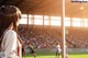 A woman standing in front of a soccer field.