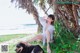 A woman sitting on the beach next to a dog.