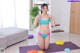 A woman in a bikini sitting on a yoga mat.