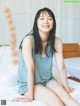 A woman sitting on top of a bed in a bedroom.