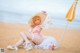 A woman in a pink bikini sitting on a beach.