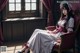 A woman in a white dress sitting on a red chair.