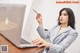 A woman sitting at a desk with a laptop and a pen.