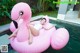 A woman laying on a pink flamingo floating in a pool.